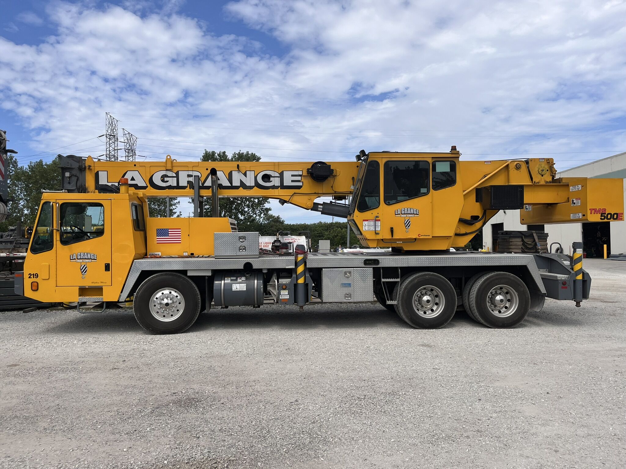 A long yellow all-terrain crane outside during the daytime. The crane has the words "La Grange" printed on its side.