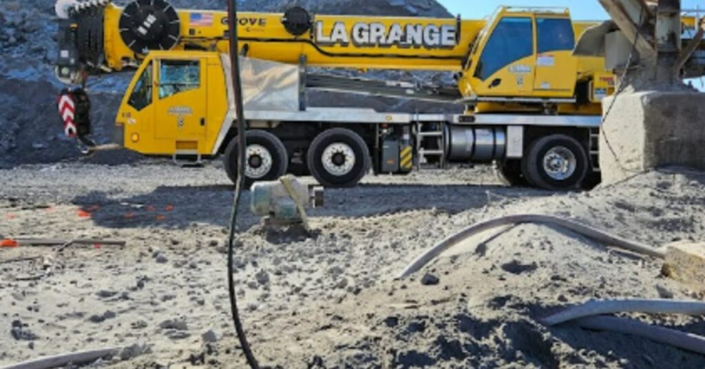 A yellow crane on a construction site during the daytime. The words "La Grange" are printed on the crane.